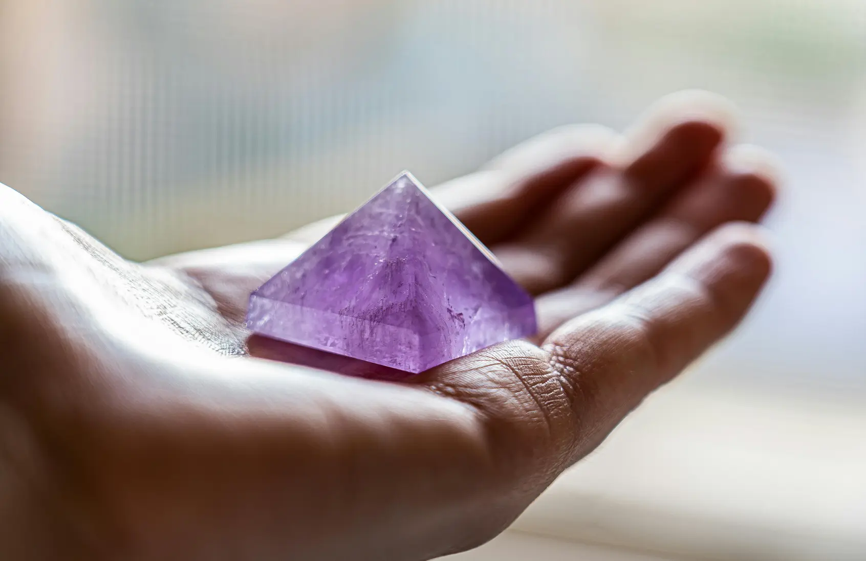Mãos segurando cristais em um ambiente sereno e com luz natural